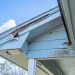 Rotted wood fascia and soffit exposed at the roofline of a home before repairing wood rot and painting the exterior.