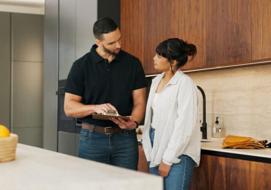 A contractor reviews a house painting warranty and quote with a homeowner in her kitchen.